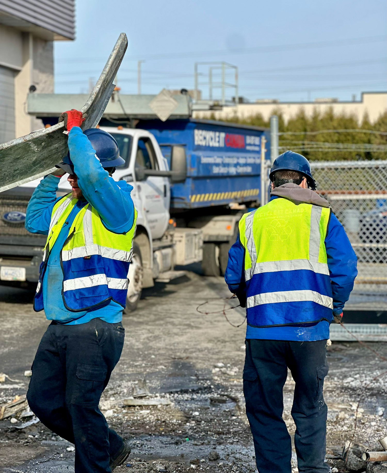 Recycle It Canada crew cleaning up a construction site with the recycle it blue truck behind them