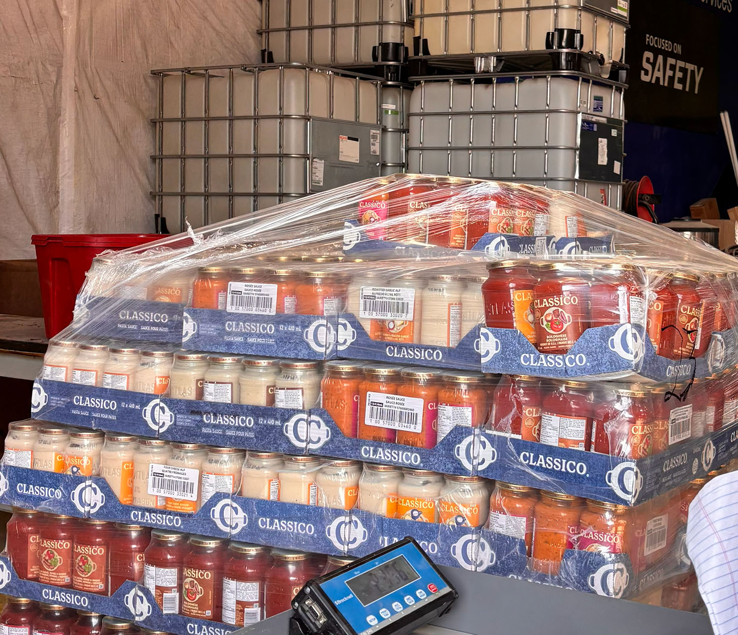 Glass containers of pasts sauce shriked wrapped and being weighed in a warehouse ready for disposal